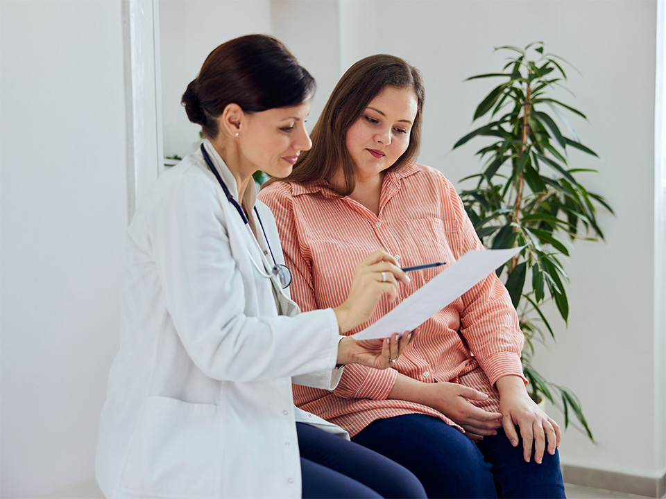 Corewell Health fertility specialist stands next to her patient as they speak in an exam room