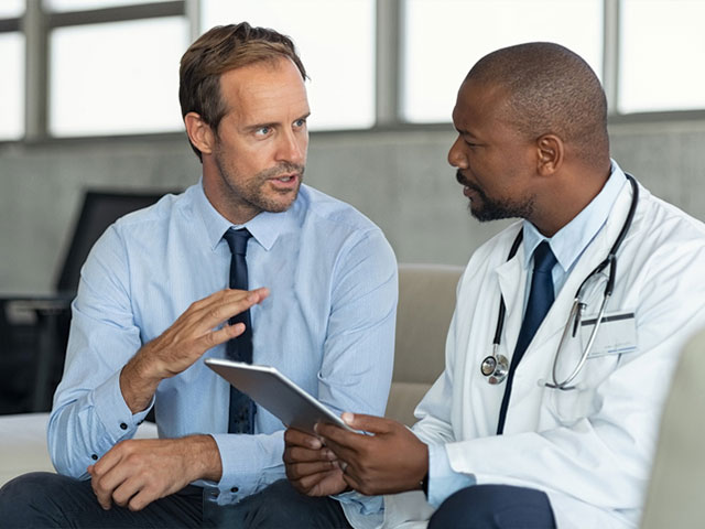 Two doctors discussing medical topics while sitting together on a couch.