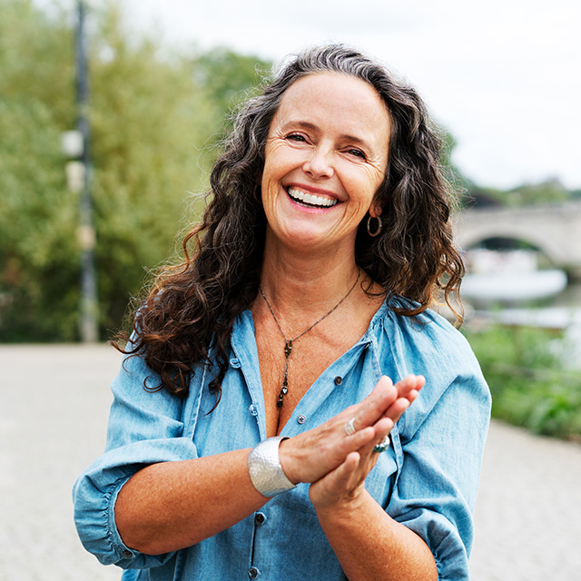 A woman with long curly hair smiles warmly at the camera.