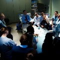 A group of residents gathered around a table in a room, engaging in conversation and sharing experiences.