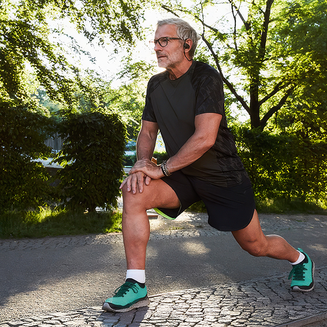 Person stretching outdoors before exercise, highlighting activities and movement that can contribute to knee pain.