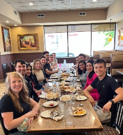 2023-2024 fellows seated at a table, partaking in a dinner outing and engaging in lively conversation.