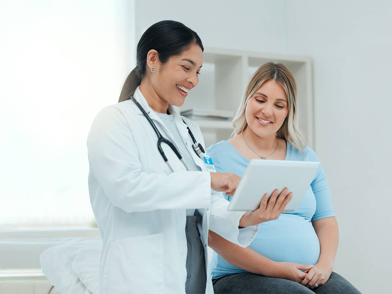 Smiling Corewell Health maternal-fetal medicine specialist speaks with her patient in an exam room