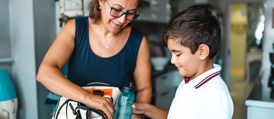A woman helps a child with a backpack.