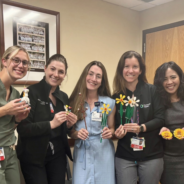 Staff and fellows pose for a picture while holding flower themed items