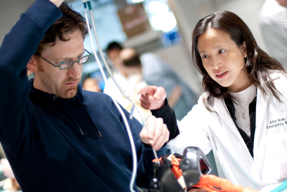  A man and woman in lab coats collaborate on a project, embodying teamwork in emergency medicine training.