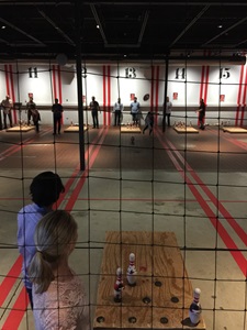 People enjoying a competitive game of darts in a vibrant indoor arena atmosphere.