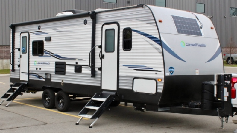 Photo of a Corewell Health Employer Services mobile unit, a white colored camper trailer with the Corewell Health logo on the side