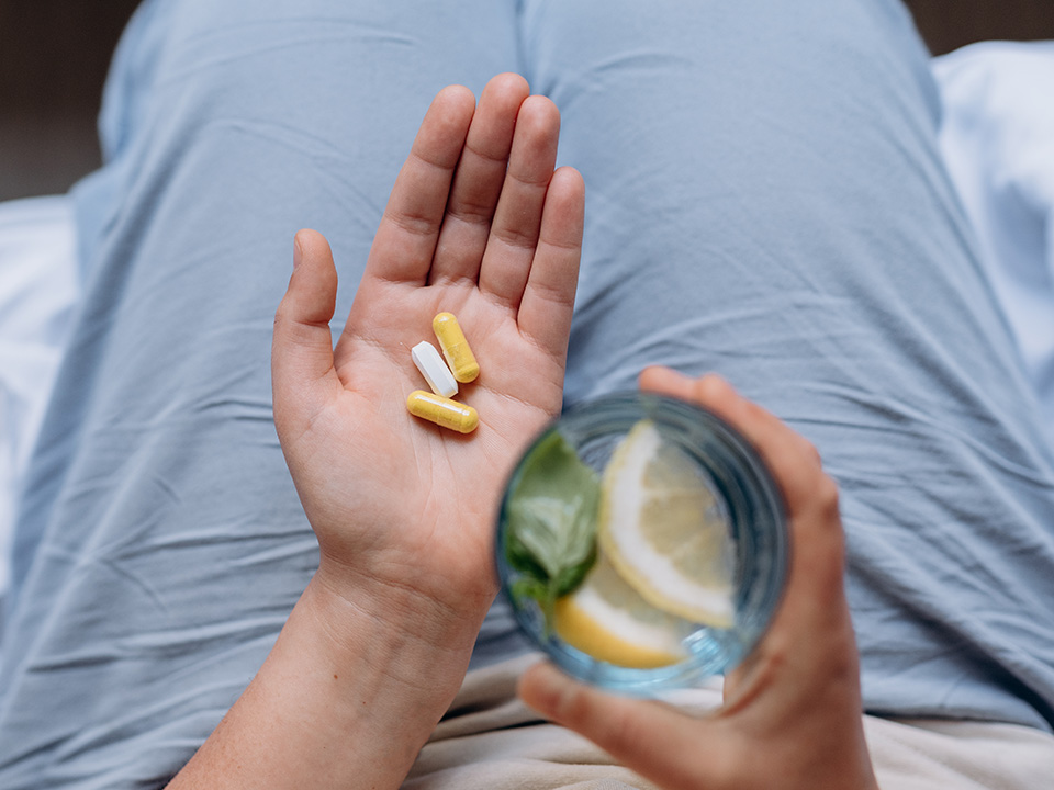 Hand holding three supplement pills