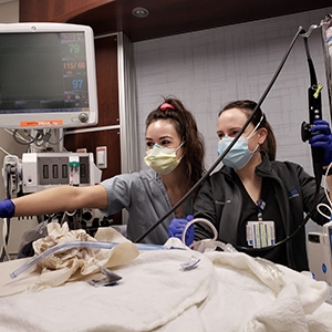 Two women in scrubs engage in patient care, exemplifying dedication and professionalism in a trauma center.