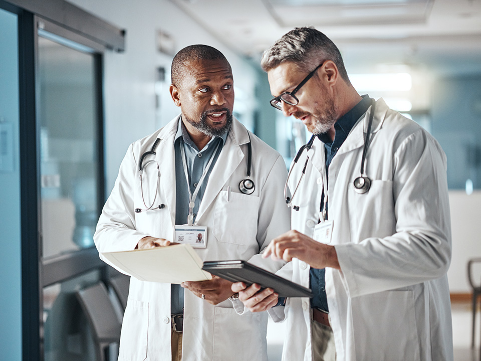 Two Corewell Health lung transplant surgeons stand next to each other as they discuss patient care