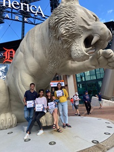 A group of individuals smiling and posing together in front of a majestic tiger statue during a wellness retreat.