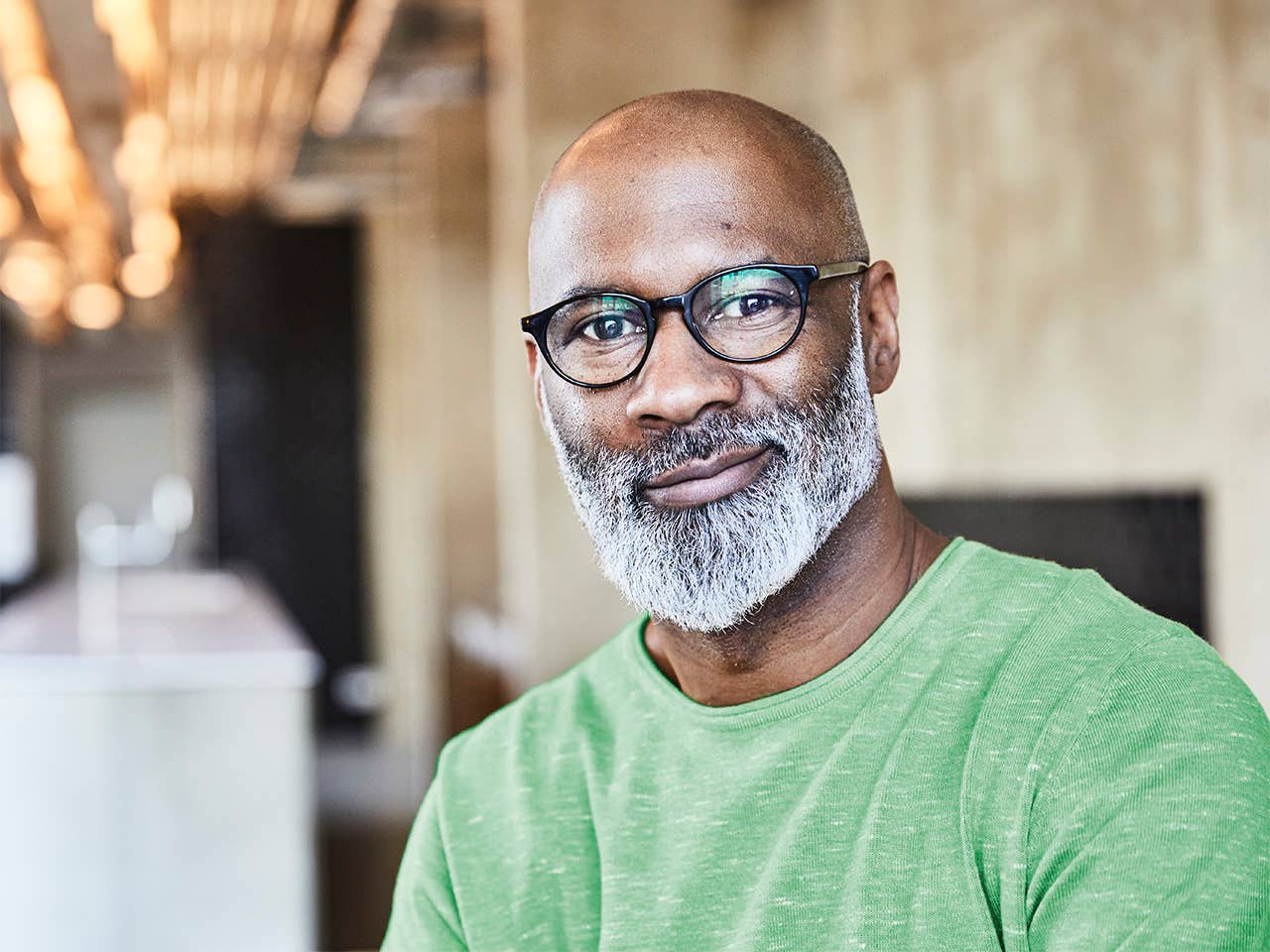 Black man with a grey beard smiles while looking at the camera