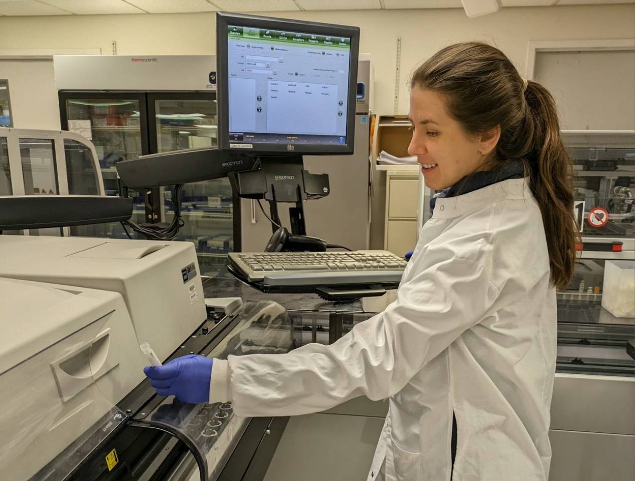 A woman wearing a lab coat presents a tray, indicating a hands-on approach to her research or project.