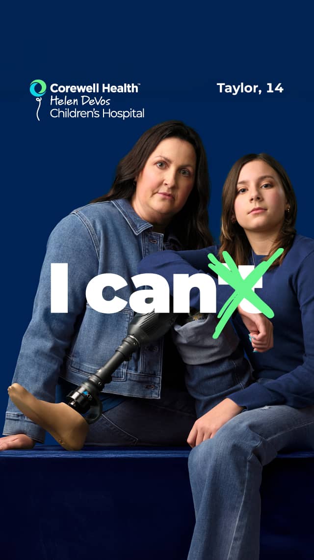 Taylor, a 14 year old patient, sits on a blue box with her prosthetic leg propped up, with her mom standing beside her