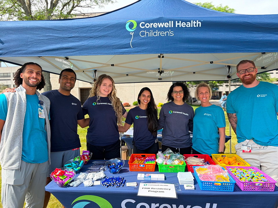 PM&R residency team at a Corewell Health Children’s community event booth with activity supplies and resources.