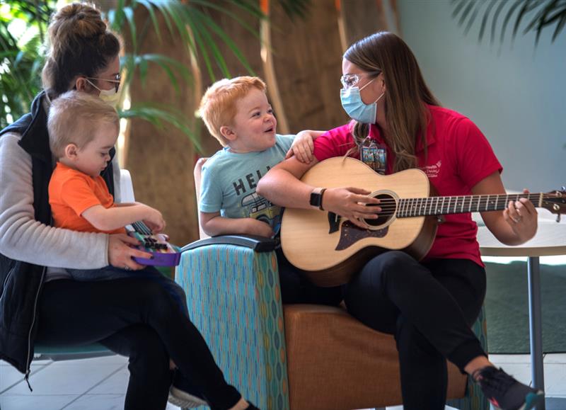 women playing guitar for a smiling little boy