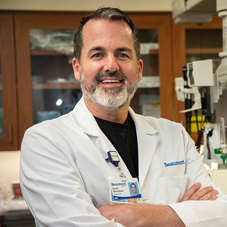 Dr. Dave Donaldson, an EM Faculty Mentor, stands in a lab coat before a computer, embodying professionalism in academia.