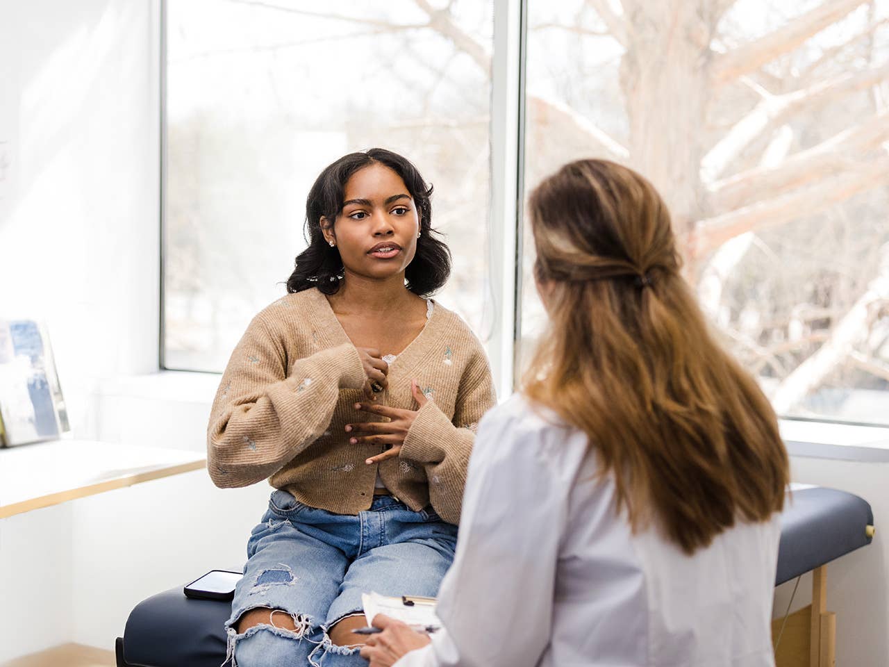Teenage girl talking to a medical professional about her feelings and symptoms.