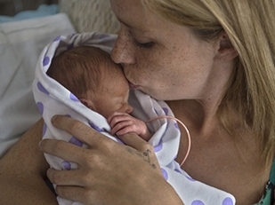 Mother holding very small baby wrapped in a blanket.