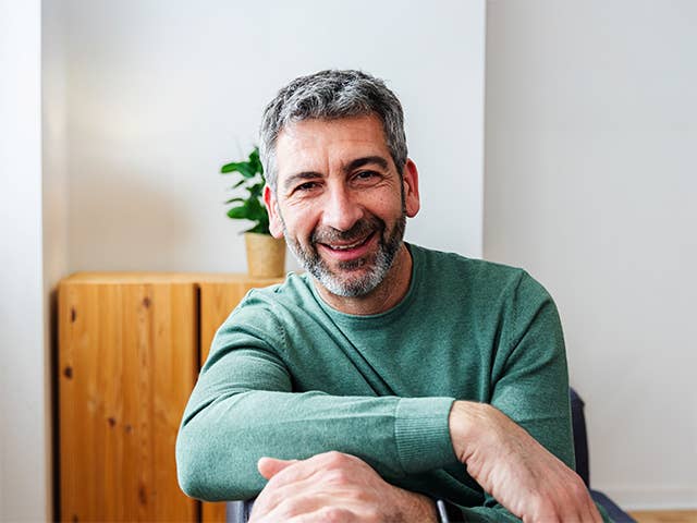 A man sitting in a chair, smiling warmly.
