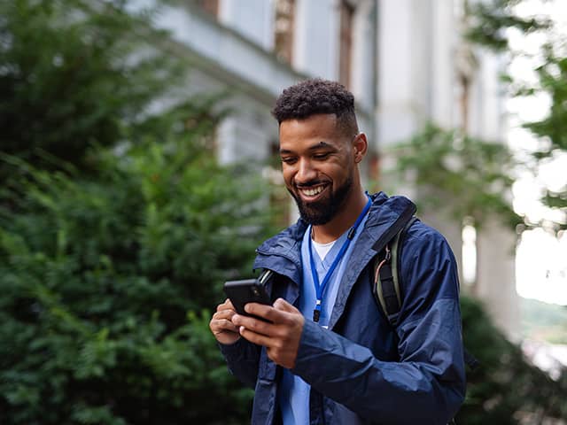 A man is looking at his phone for information as he is walking outside