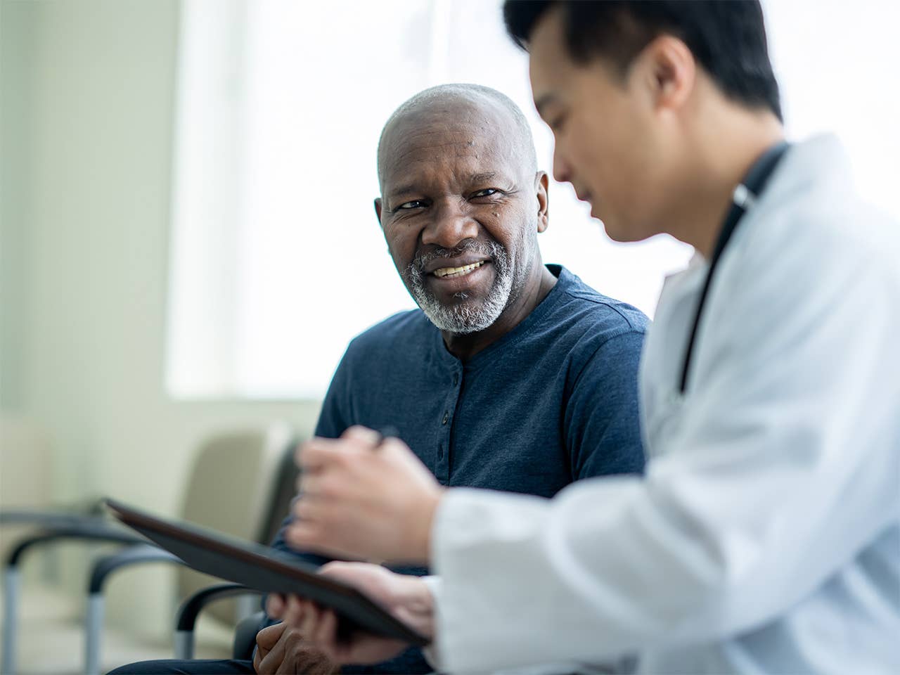 Smiling Black man wearing a navy blue shirt speaks with a Corewell Health doctor