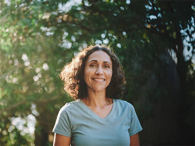 Smiling woman in a light blue shirt with shoulder length curly brown hair