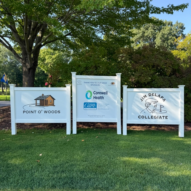 Wooden signs in the grass showing sponsor names at a golfing event
