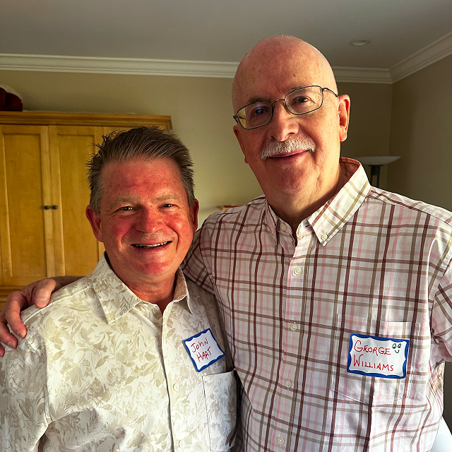 Two attendees wearing name tags pose together indoors at a community gathering.