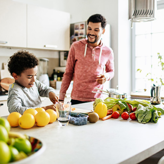 father and son in kitchen making a snack with produce