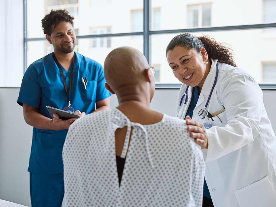Smiling Corewell Health epilepsy specialist speaks with a patient in an examroom