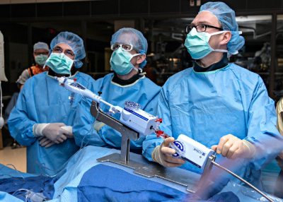 Three cardiologists are in the middle of a procedure and looking up at a screen