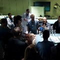 A group of residents in a room, with a man in a white coat leading the discussion among them.