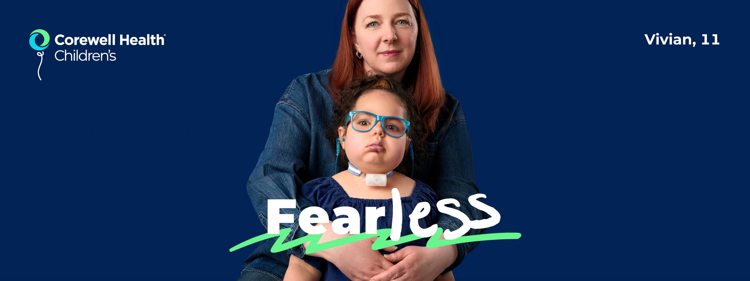 Vivian, an 11 year old patient wearing a blue blouse and light blue glasses, stands with a walker with her mom behind her