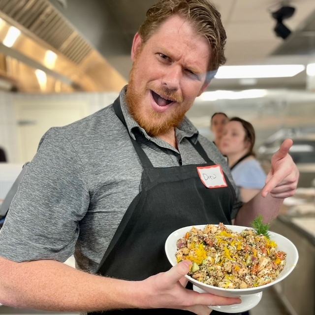 male chef proudly displaying a dish he made 