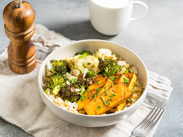 A bowl filled with broccoli, cauliflower, and pieces of chicken, showcasing a colorful and nutritious meal.