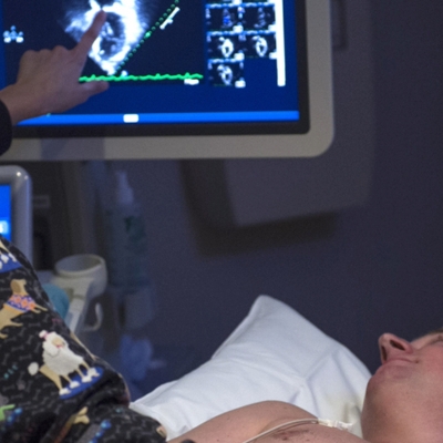 Health care provider looking at imaging scan with patient in bed.