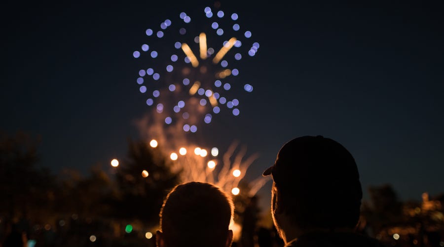 Um homem e uma criança assistindo aos fogos de artifício em comemoração ao 4 de Julho.