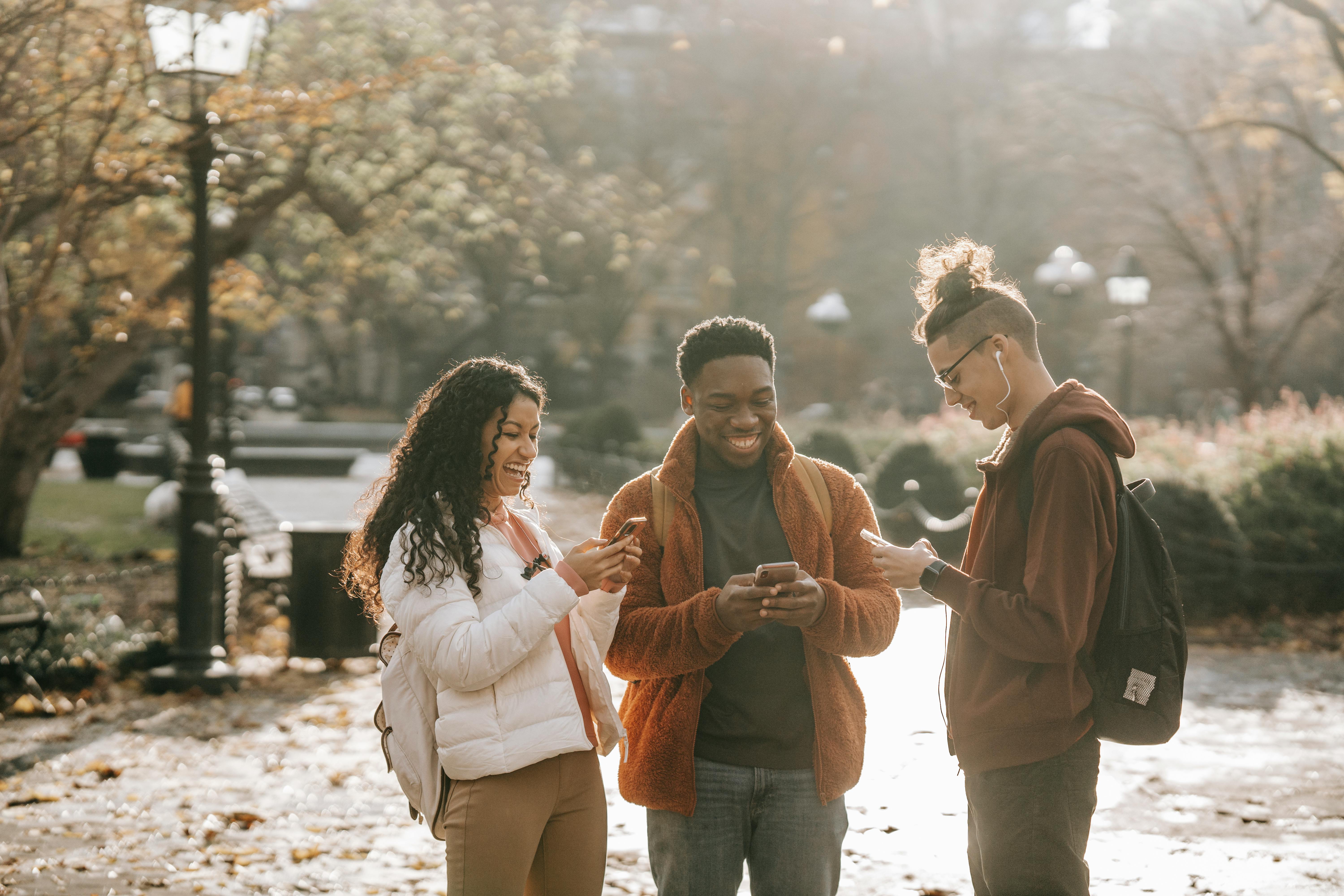 Grupo de amigos conversam na rua de forma informal, utilizando british slangs pelo celular.