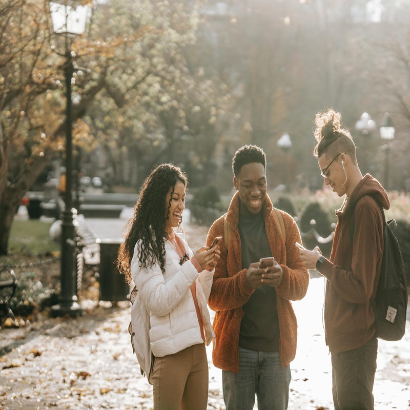 Grupo de amigos conversam na rua de forma informal, utilizando british slangs pelo celular.