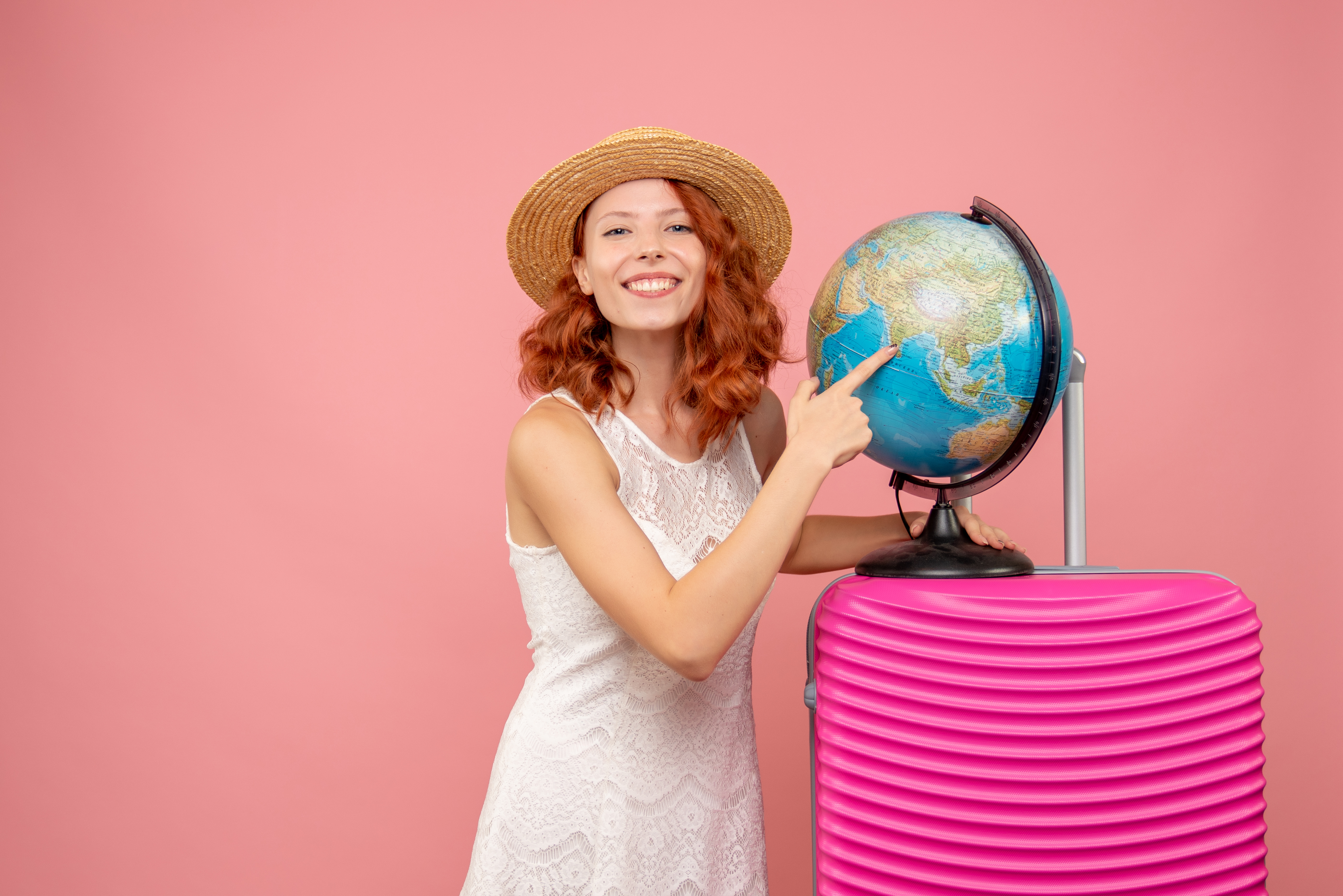 Mulher ao lado de um globo terrestre, com uma mala  rosa pronta para viajar em inglês