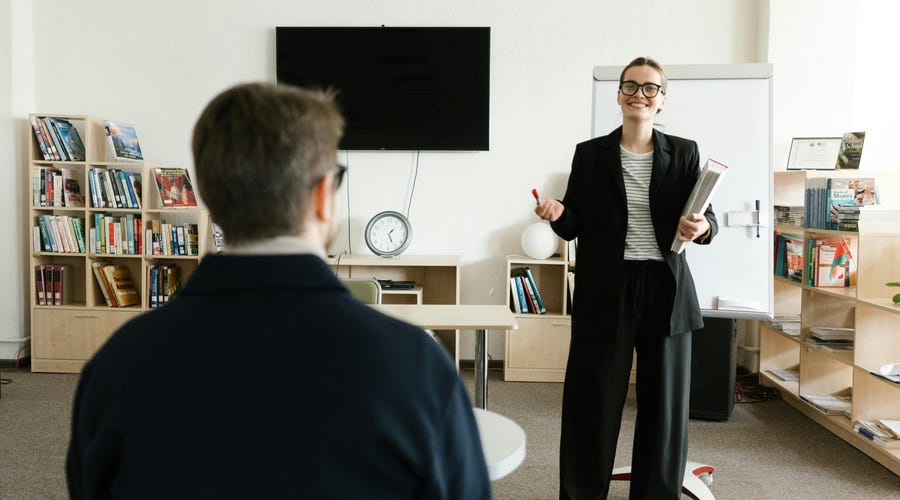 Mulher de traje social falando sobre o curso de negócios e aprimoramento profissional que realizou.