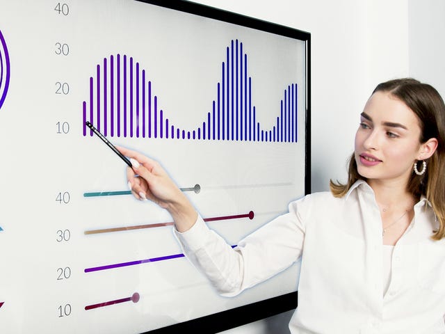 Mulher se apresentando para uma equipe com gráficos e dados.