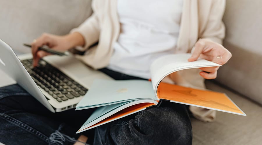 Mulher estudando com um caderno e computador as palavras sem tradução em inglês.