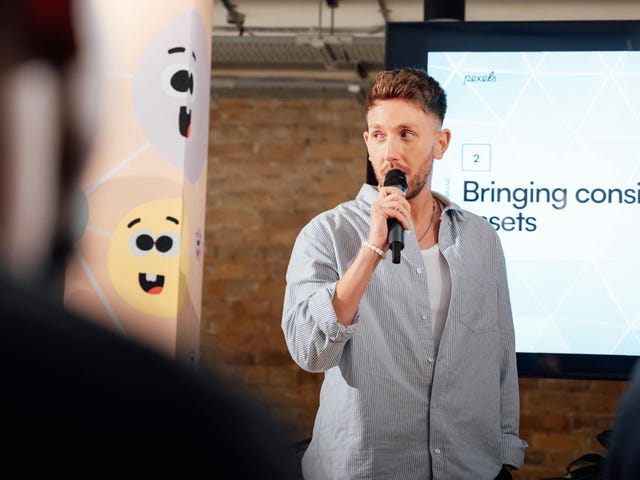 Homem segurando um microfone utiliza seus conhecimento de um curso de apresentação com a ajuda de slides.