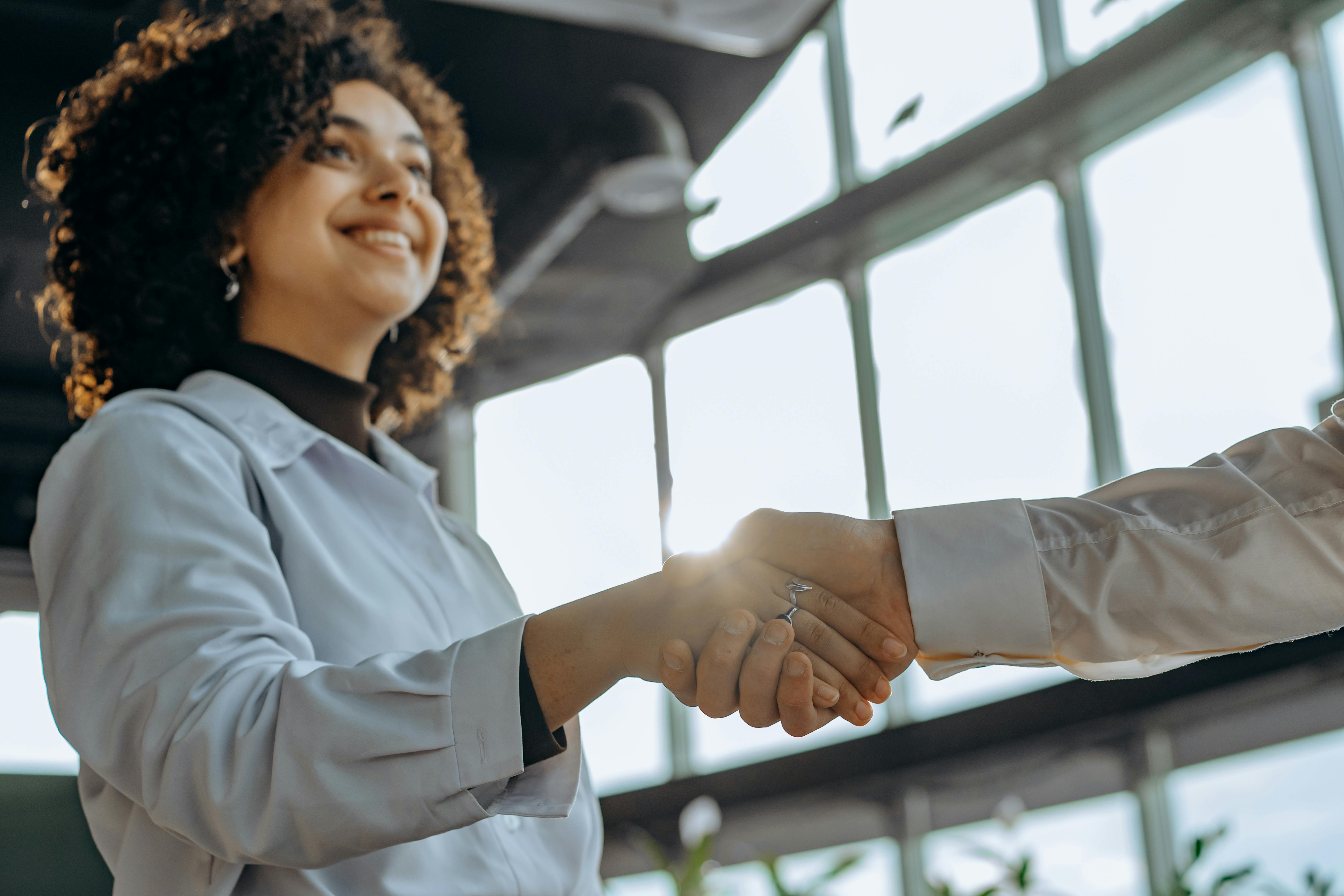 Mulher jovem em um aperto de mãos após seu curso de negociação.