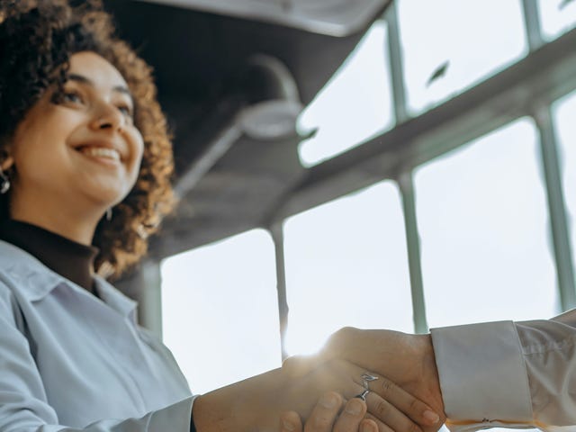 Mulher jovem em um aperto de mãos após seu curso de negociação.