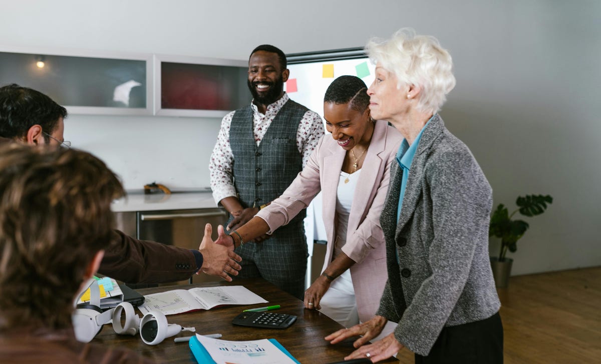 Empresários reunidos em uma sala apertando a mão durante uma negociação.