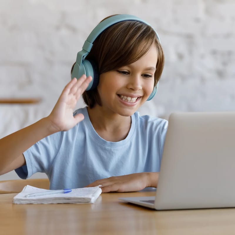 Criança sentada com laptop aprendendo inglês online com a escola de idiomas Berlitz.